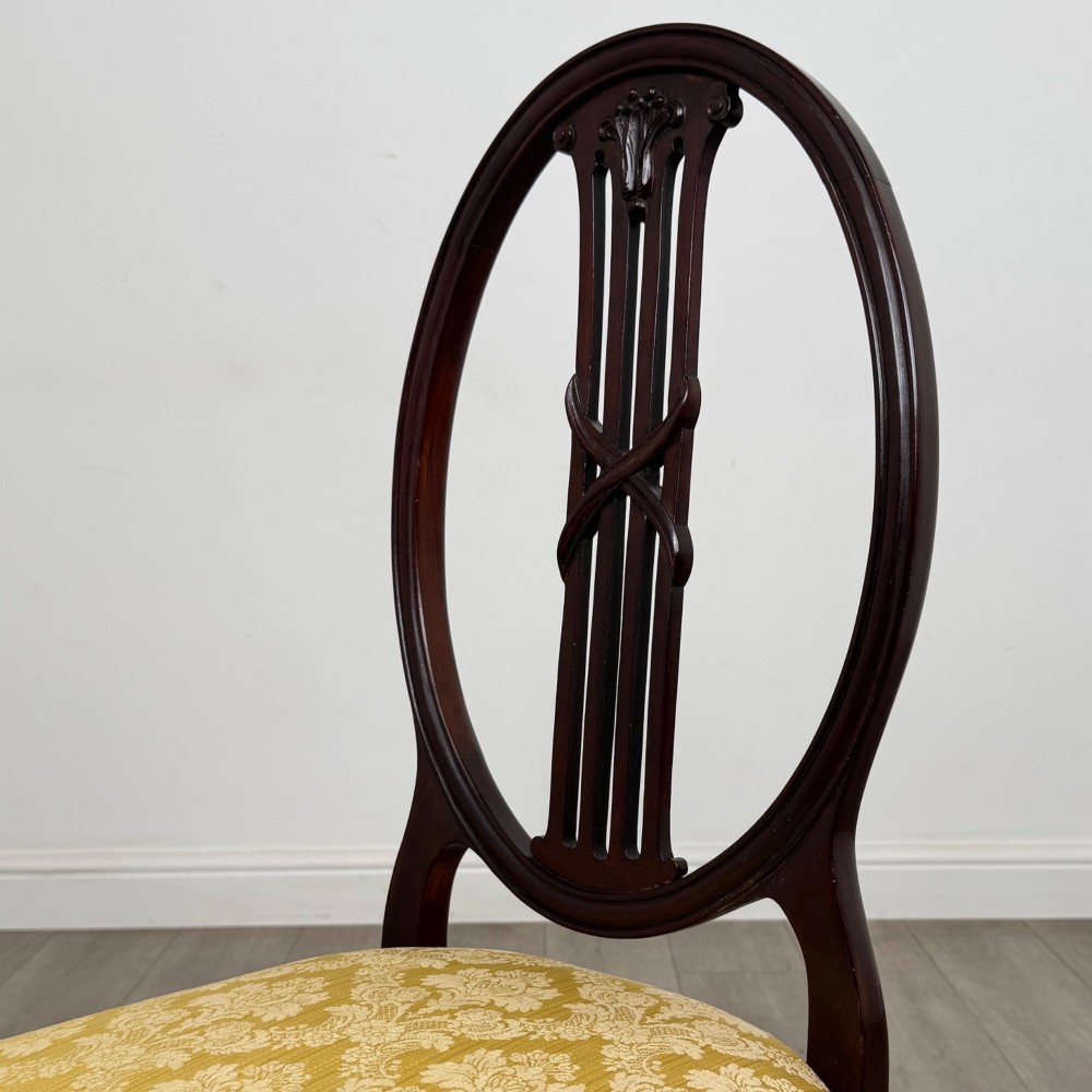 A set of four dark mahogany dining chairs with carved oval backs, slender vertical splats, and gold damask upholstered seats. View IV