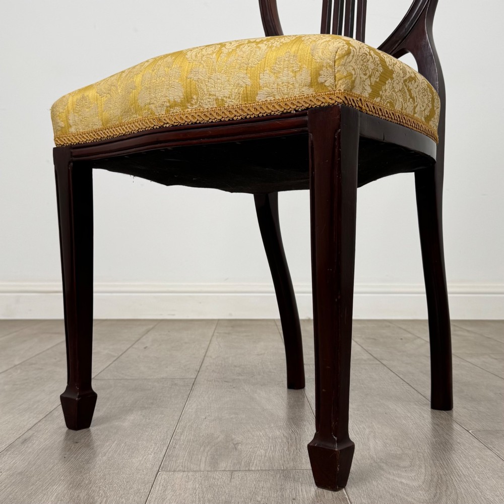 A set of four dark mahogany dining chairs with carved oval backs, slender vertical splats, and gold damask upholstered seats. View V