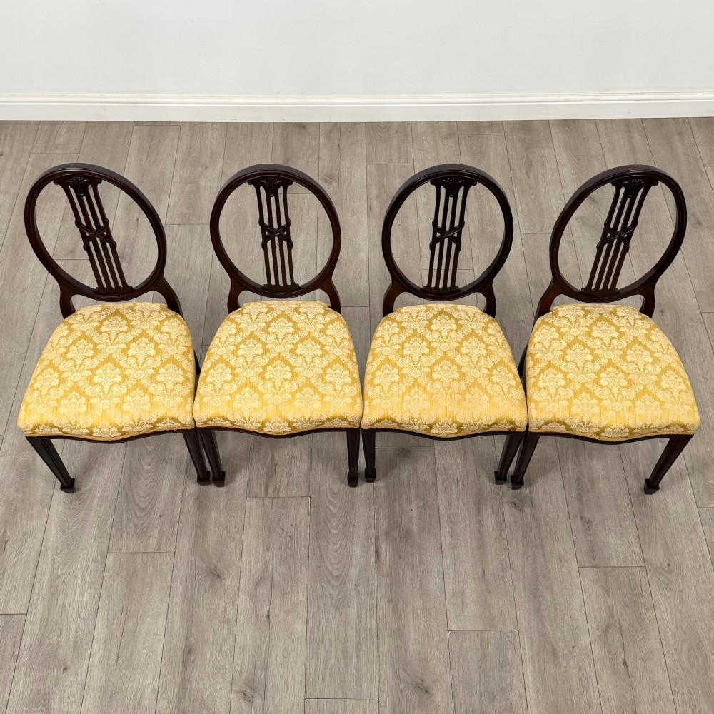 A set of four dark mahogany dining chairs with carved oval backs, slender vertical splats, and gold damask upholstered seats. View VII