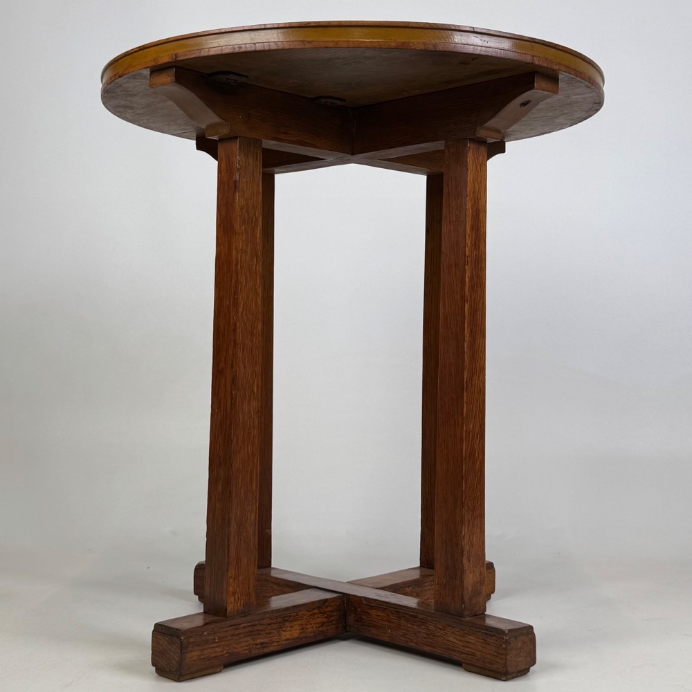 An early twentieth-century round oak side table featuring a circular top supported by straight legs and an X-frame cross base.