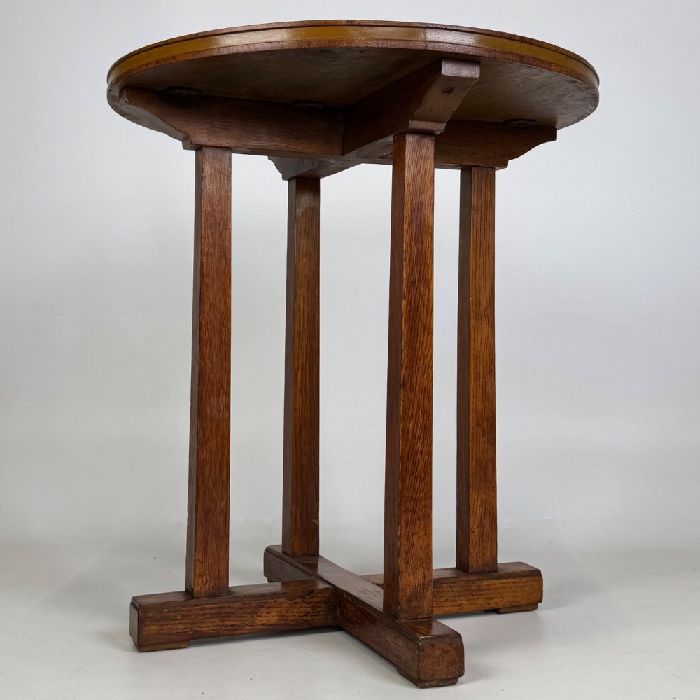 An early twentieth-century round oak side table featuring a circular top supported by straight legs and an X-frame cross base. View II