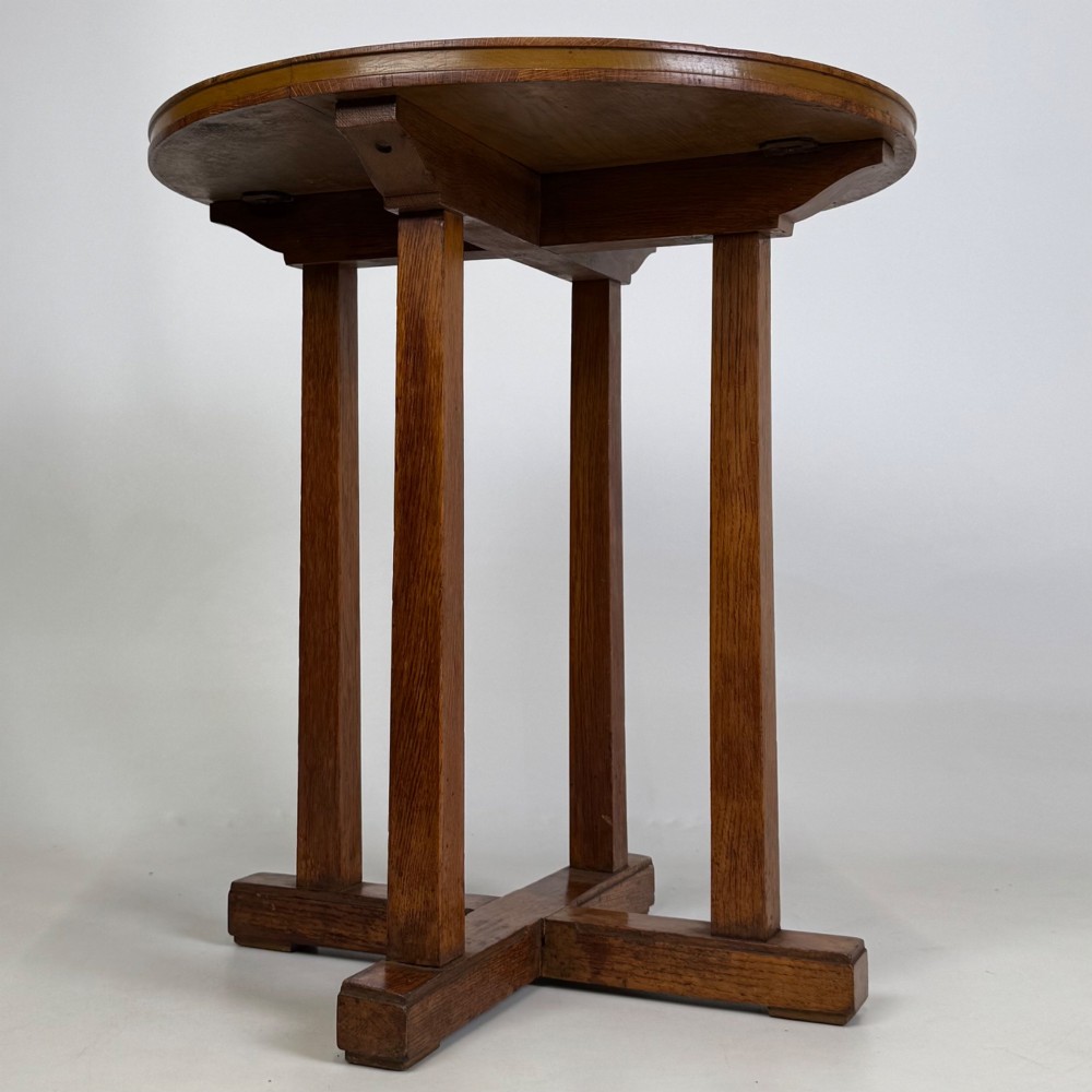 An early twentieth-century round oak side table featuring a circular top supported by straight legs and an X-frame cross base. View IV