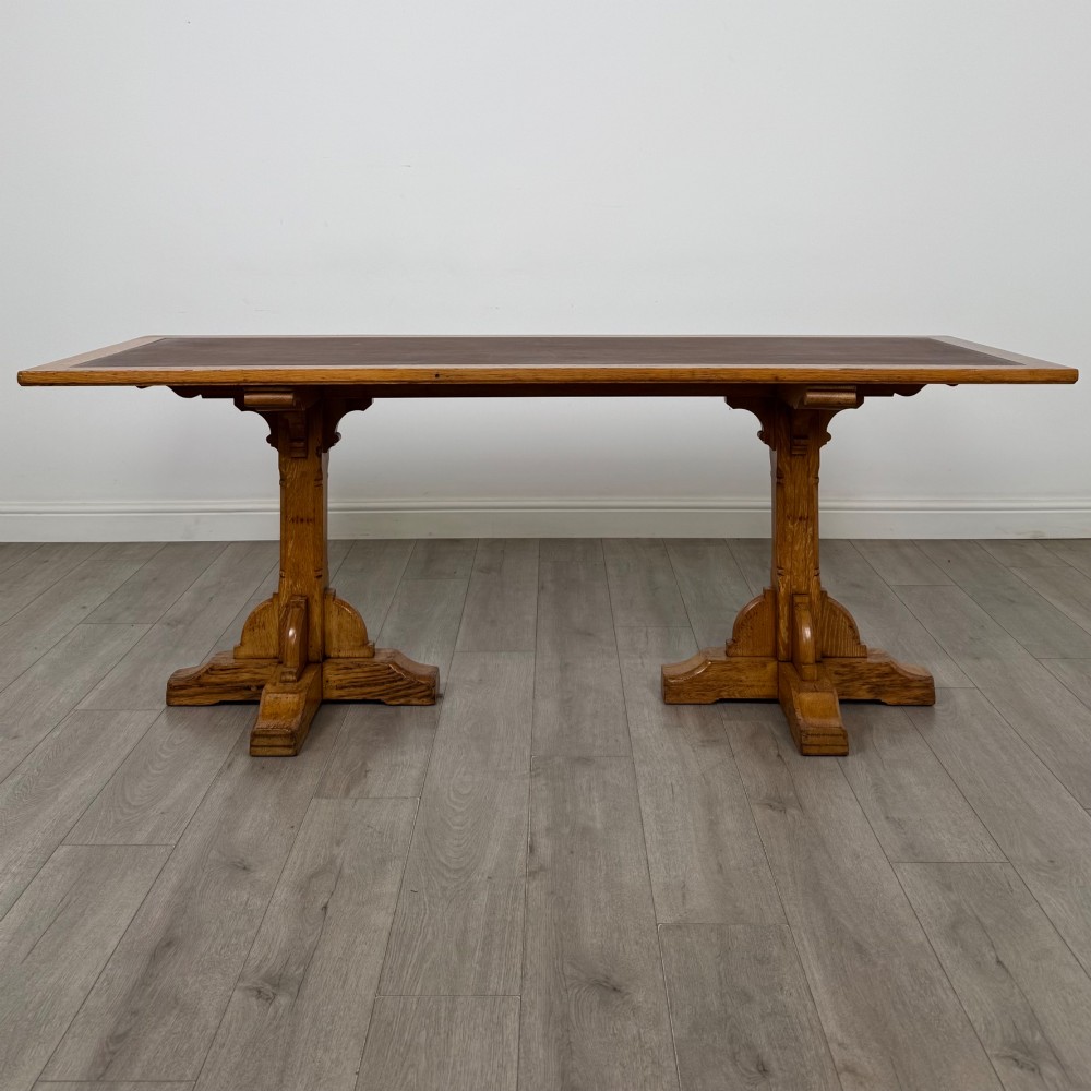 A large twentieth-century Arts and Crafts oak library table with an inset brown leather writing top resting on dual pedestal trestle supports. View II
