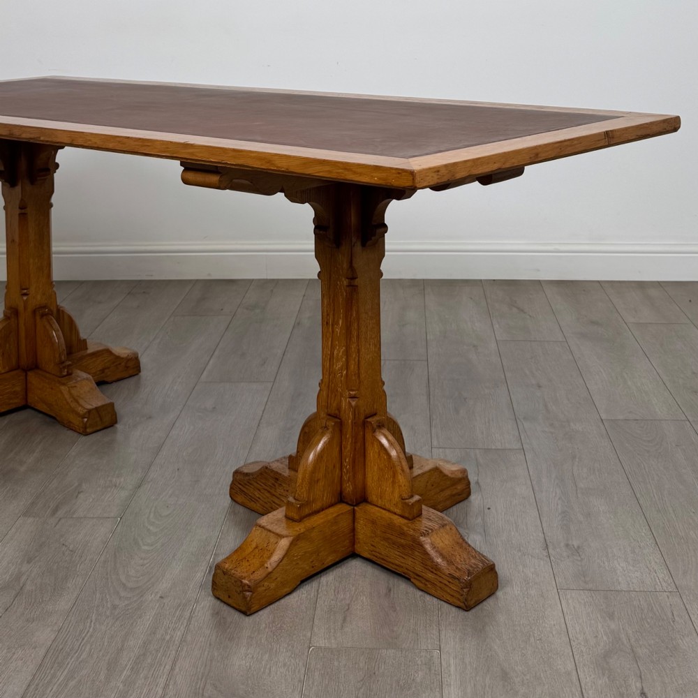 A large twentieth-century Arts and Crafts oak library table with an inset brown leather writing top resting on dual pedestal trestle supports. View V