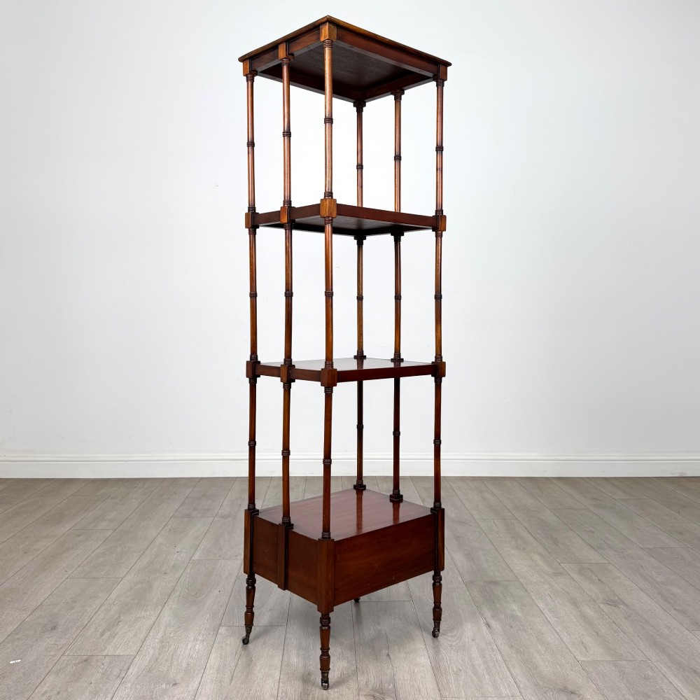 A tall, narrow 20th-century mahogany open bookcase featuring four tiered shelves supported by turned columns and a single drawer at the base raised on brass castors. View IV