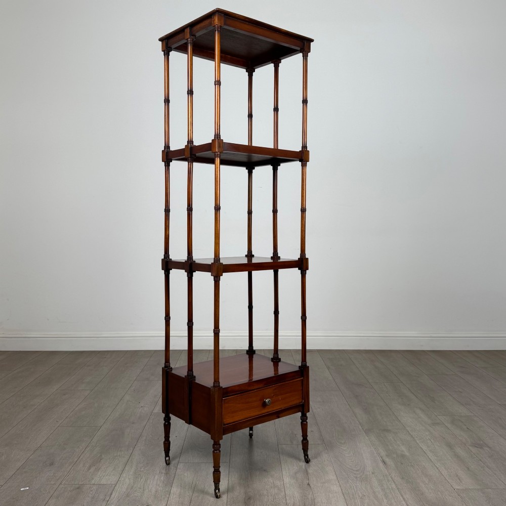 A tall, narrow 20th-century mahogany open bookcase featuring four tiered shelves supported by turned columns and a single drawer at the base raised on brass castors. View VIII