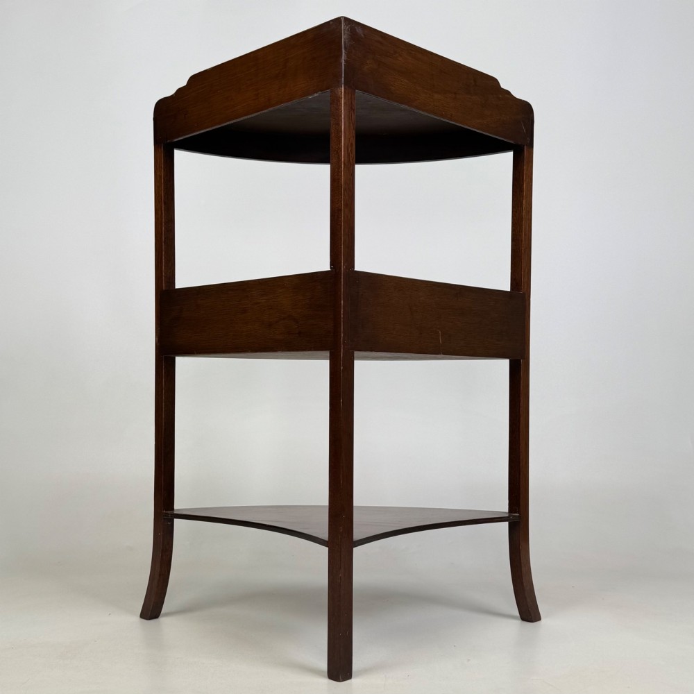 A three-tiered Georgian style mahogany corner stand featuring a curved front, single drawer with brass ring pull, and splayed legs. View III