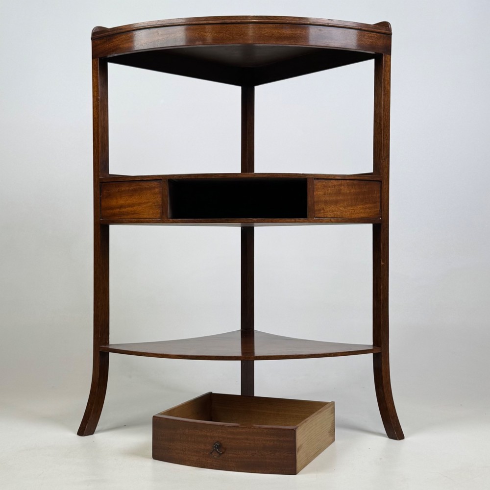 A three-tiered Georgian style mahogany corner stand featuring a curved front, single drawer with brass ring pull, and splayed legs. View VI