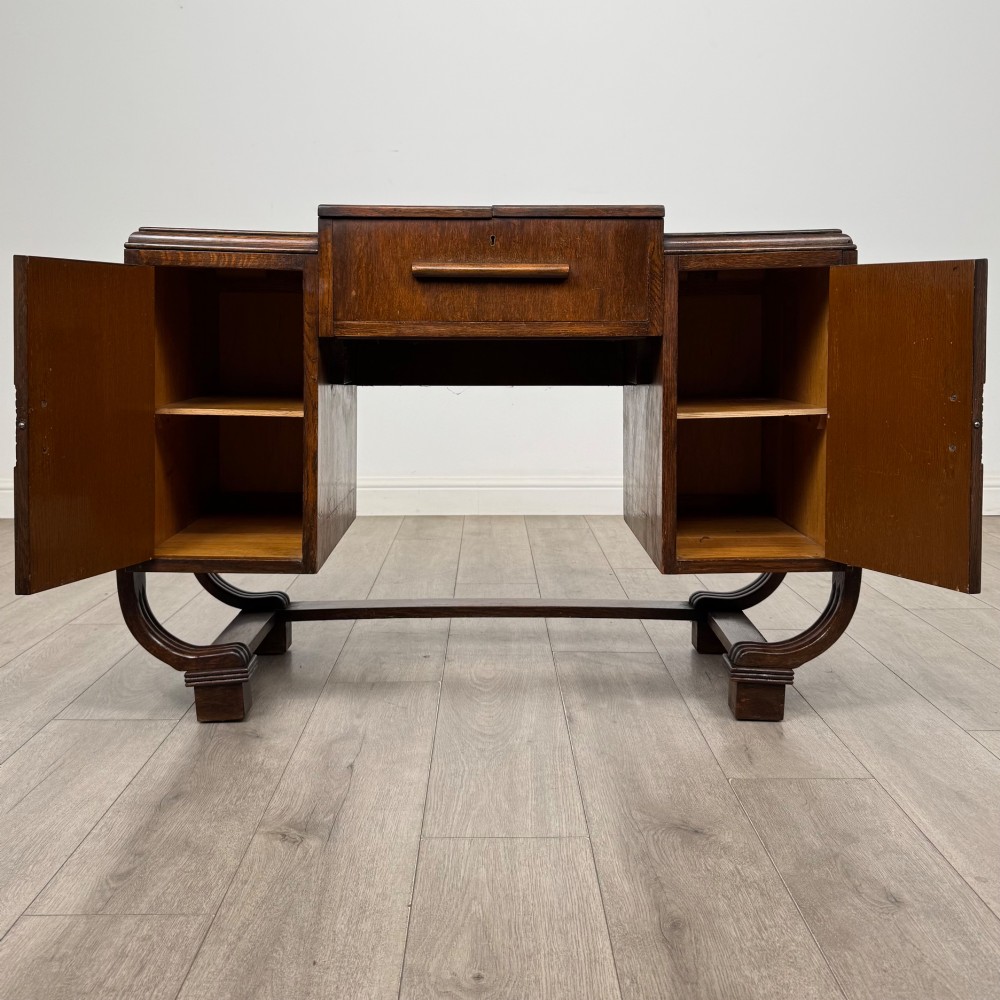 An Art Deco oak desk featuring two side cupboard pedestals supported by u-shaped curved legs and a central drawer. View II