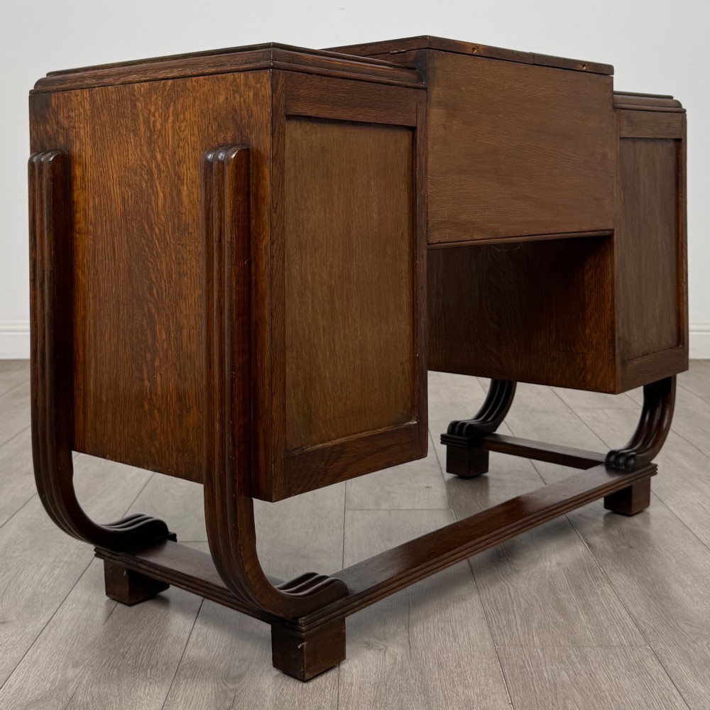 An Art Deco oak desk featuring two side cupboard pedestals supported by u-shaped curved legs and a central drawer. View V