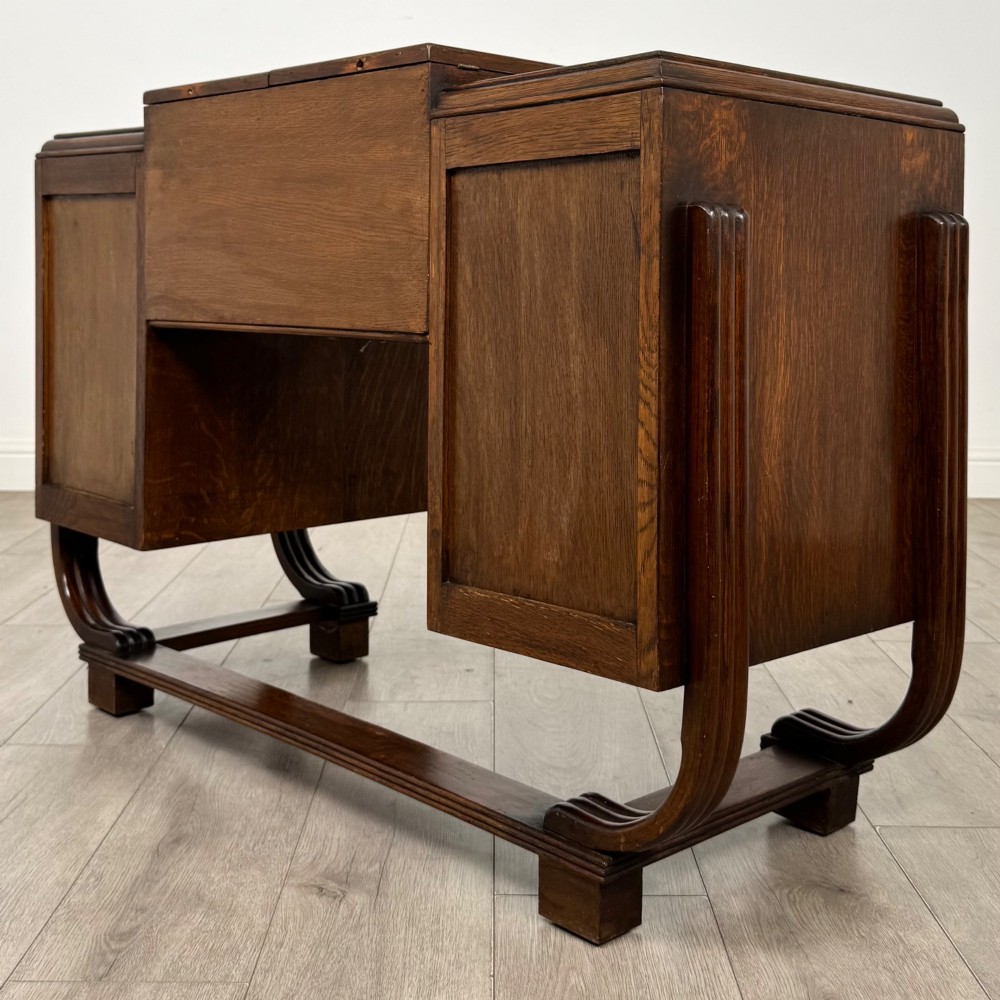 An Art Deco oak desk featuring two side cupboard pedestals supported by u-shaped curved legs and a central drawer. View VII
