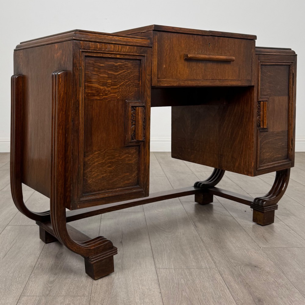 An Art Deco oak desk featuring two side cupboard pedestals supported by u-shaped curved legs and a central drawer. View IX