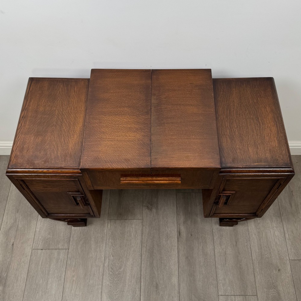 An Art Deco oak desk featuring two side cupboard pedestals supported by u-shaped curved legs and a central drawer. View X