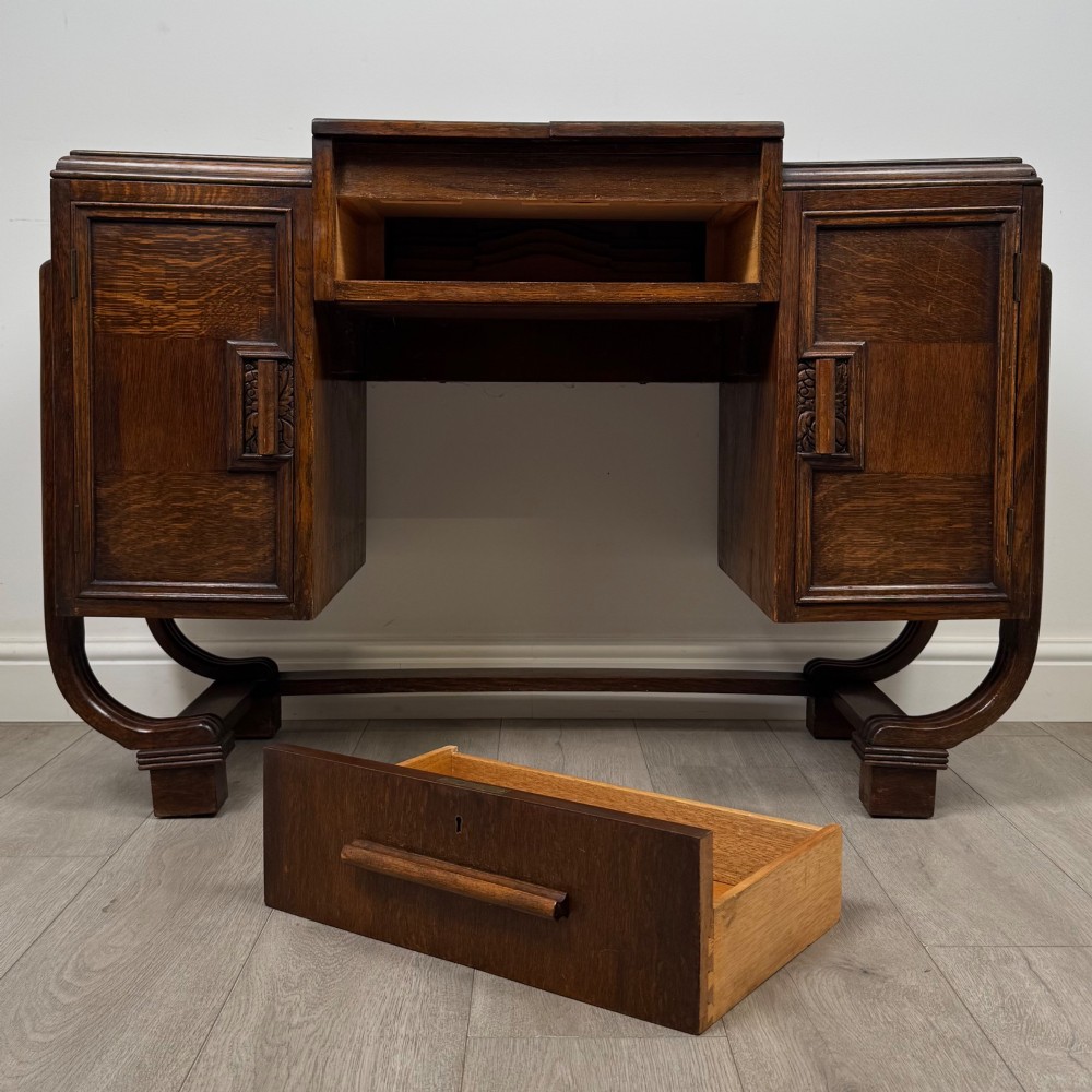 An Art Deco oak desk featuring two side cupboard pedestals supported by u-shaped curved legs and a central drawer. View XII
