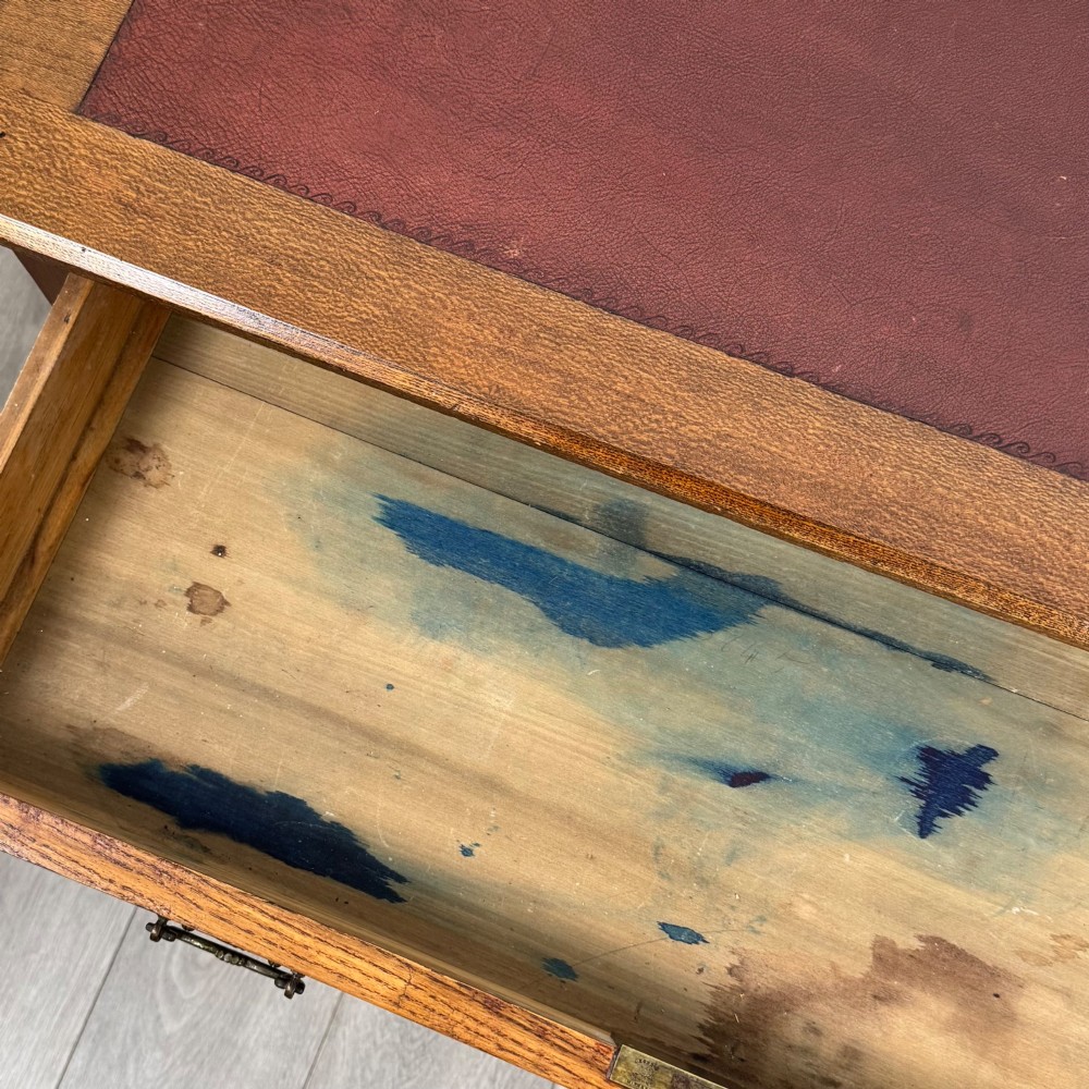 A 19th-century Victorian golden oak writing table featuring a single frieze drawer with decorative brass handles and ring-turned legs on castors. View XII