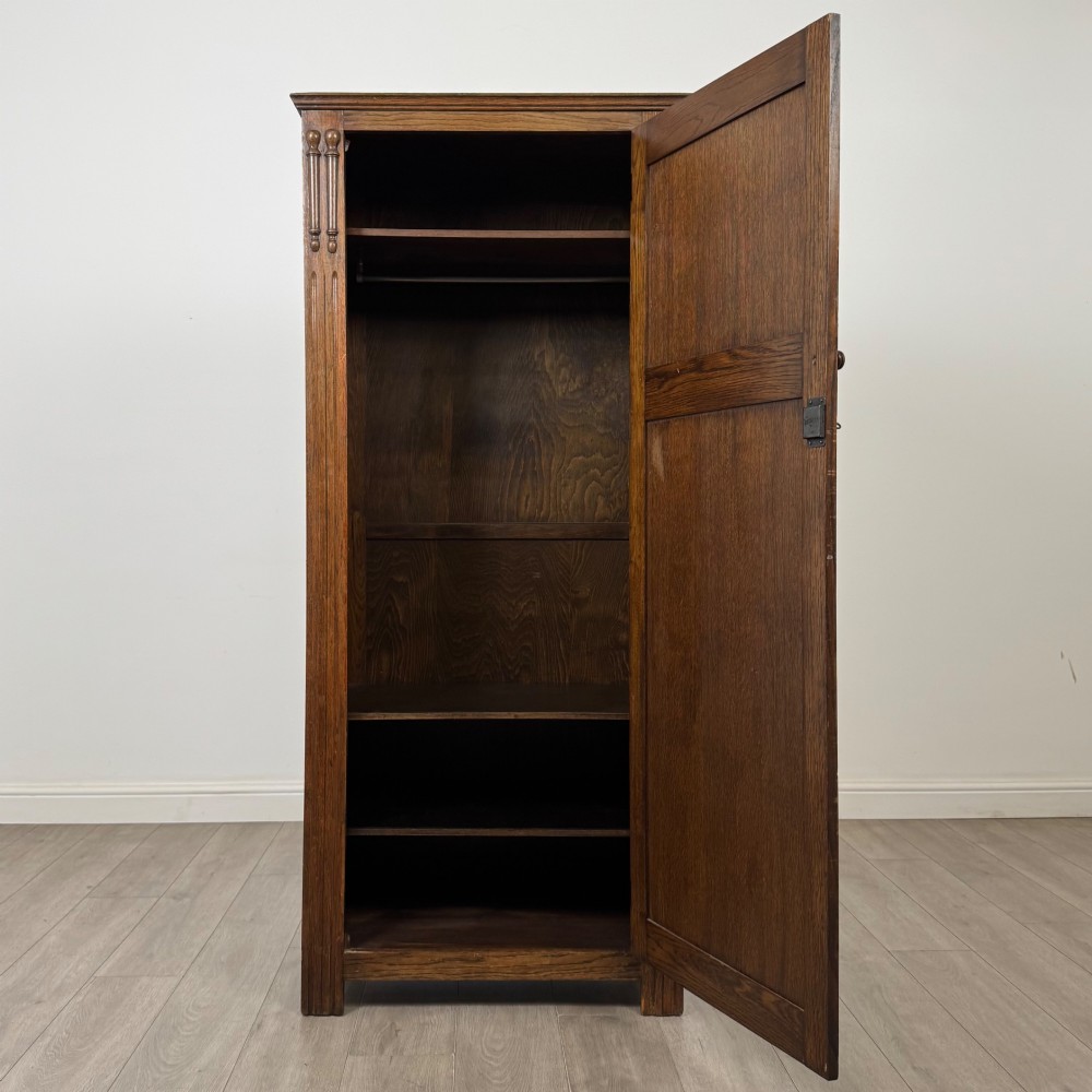 A tall, single-door Edwardian oak wardrobe featuring carved arched upper panelling and turned side columns. View II