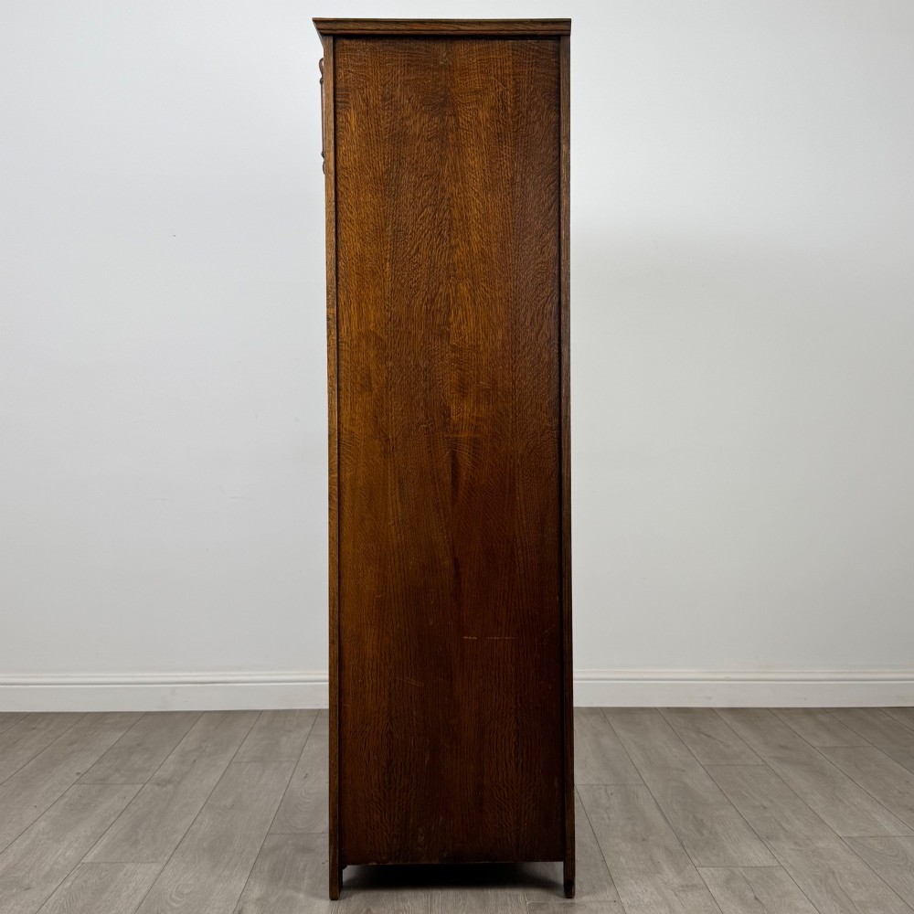 A tall, single-door Edwardian oak wardrobe featuring carved arched upper panelling and turned side columns. View IV