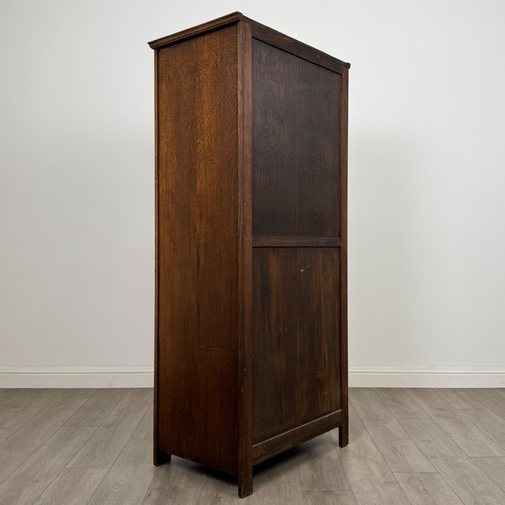A tall, single-door Edwardian oak wardrobe featuring carved arched upper panelling and turned side columns. View V