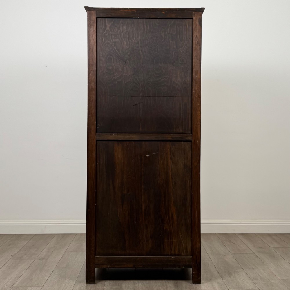 A tall, single-door Edwardian oak wardrobe featuring carved arched upper panelling and turned side columns. View VI