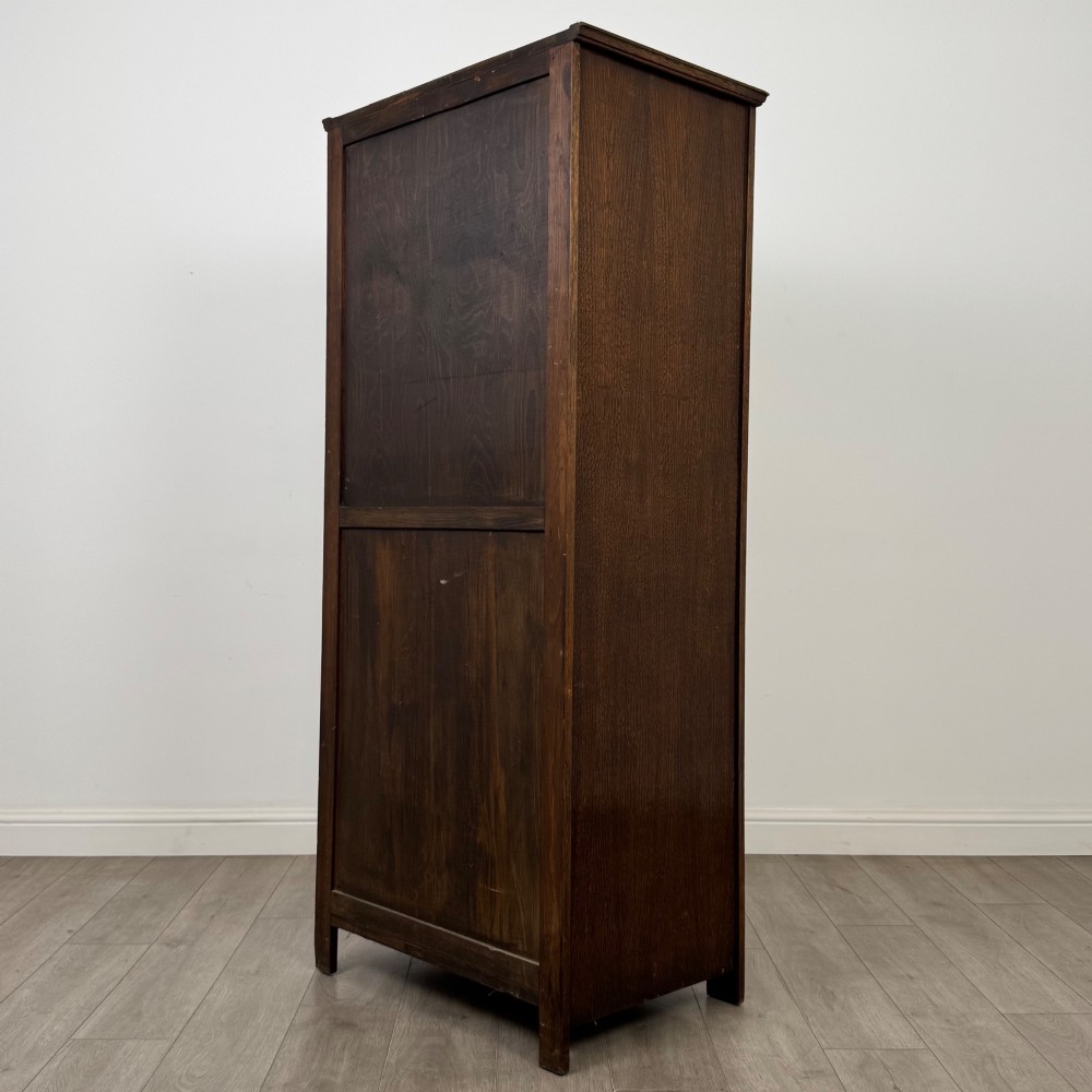 A tall, single-door Edwardian oak wardrobe featuring carved arched upper panelling and turned side columns. View VII