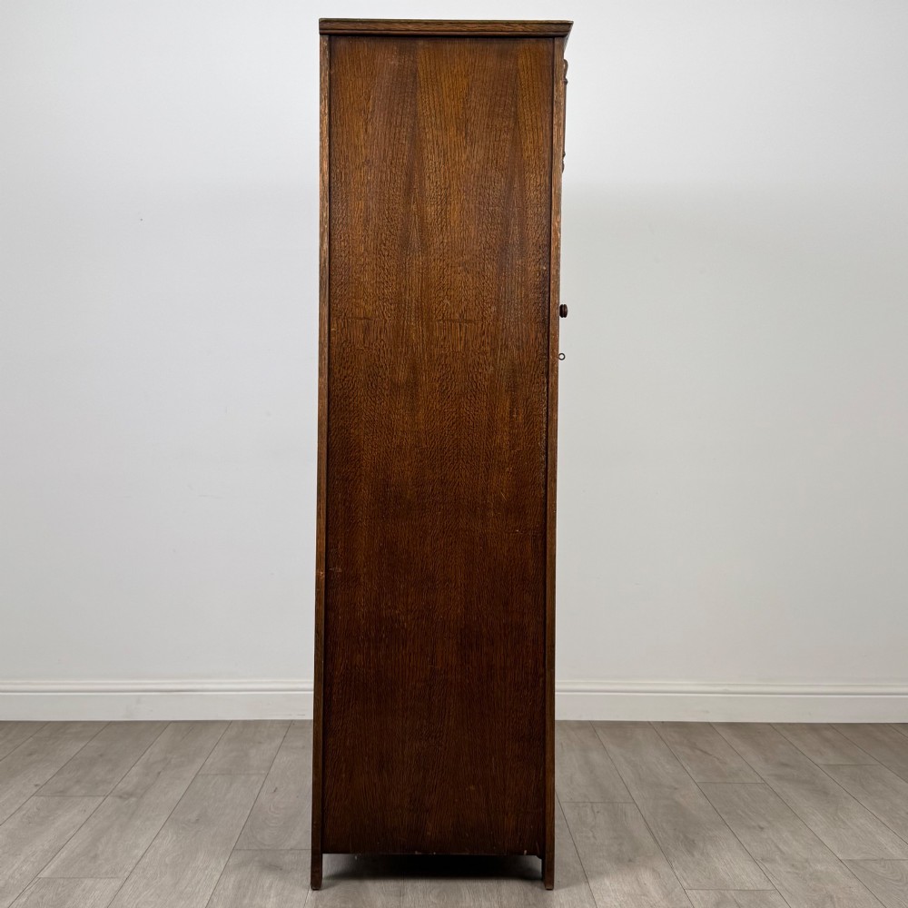 A tall, single-door Edwardian oak wardrobe featuring carved arched upper panelling and turned side columns. View VIII