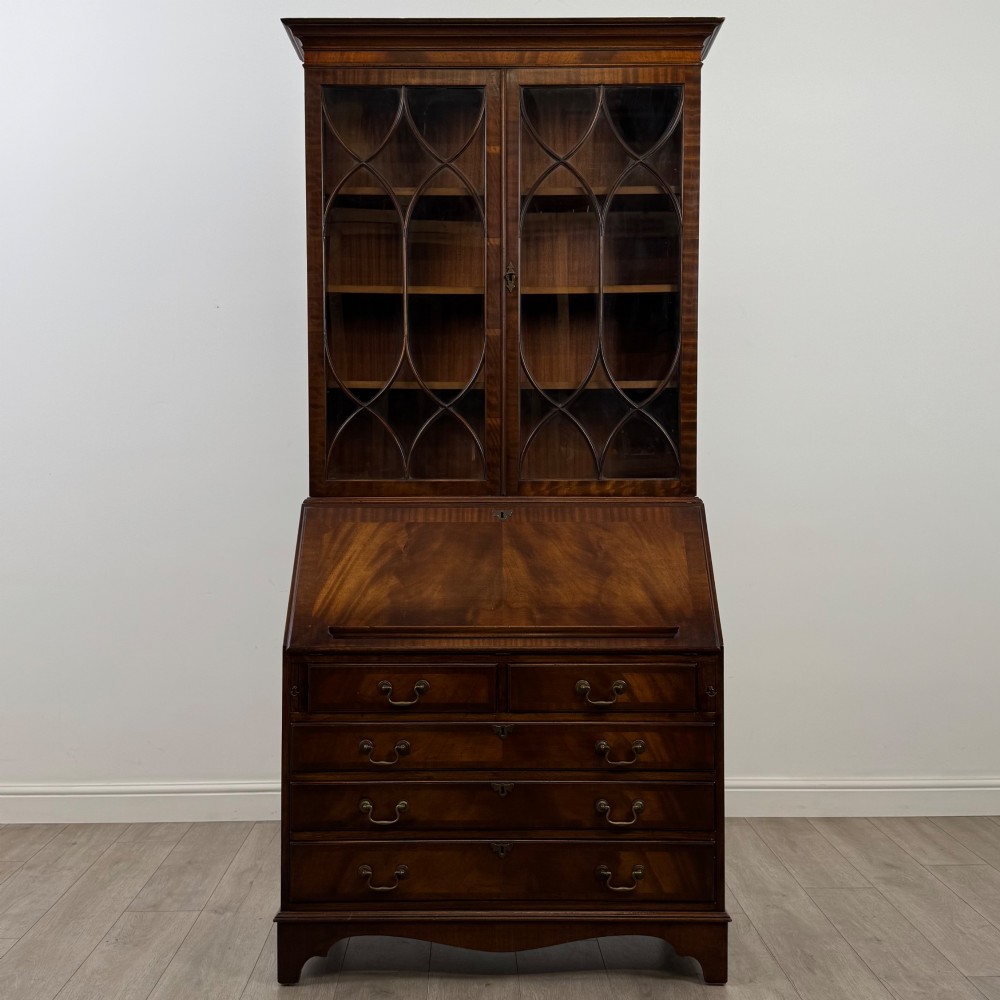 An antique mahogany bureau bookcase featuring two astragal glazed glass upper doors above a lower drop-front writing slope and four drawers. View II