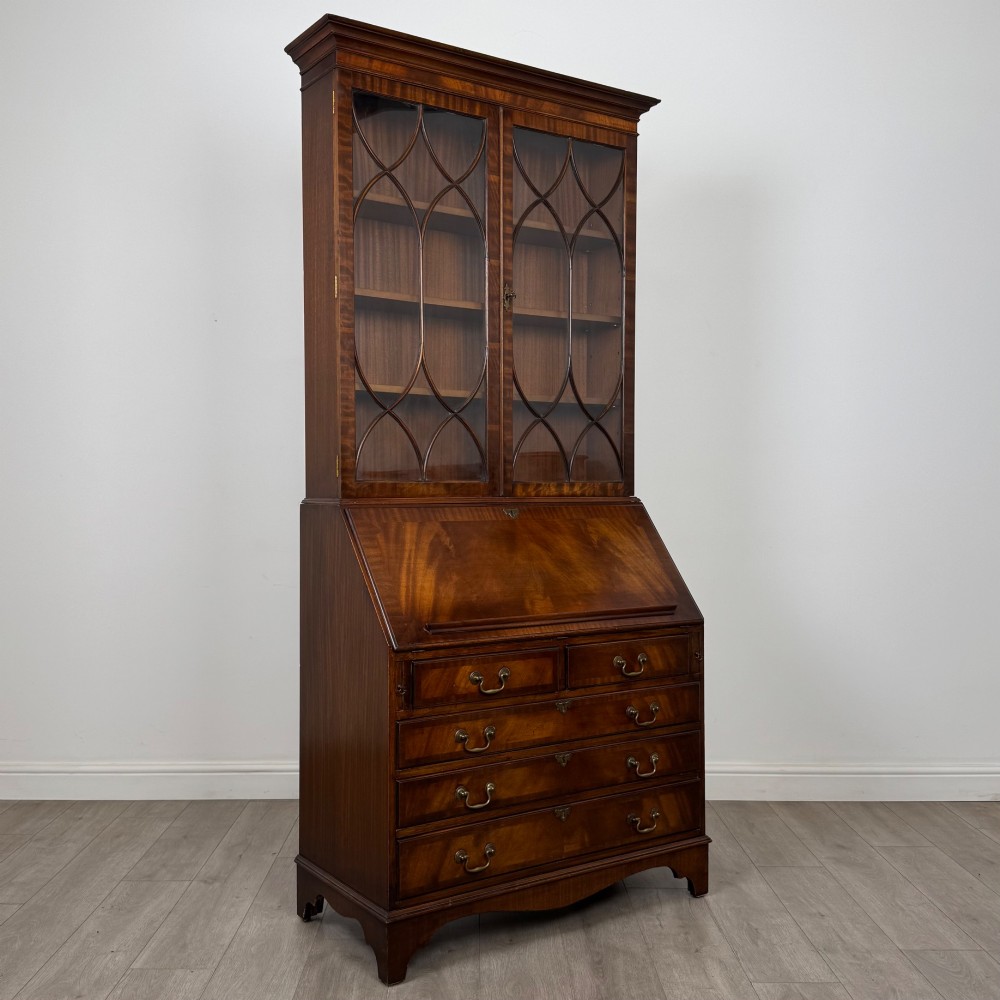 An antique mahogany bureau bookcase featuring two astragal glazed glass upper doors above a lower drop-front writing slope and four drawers. View X