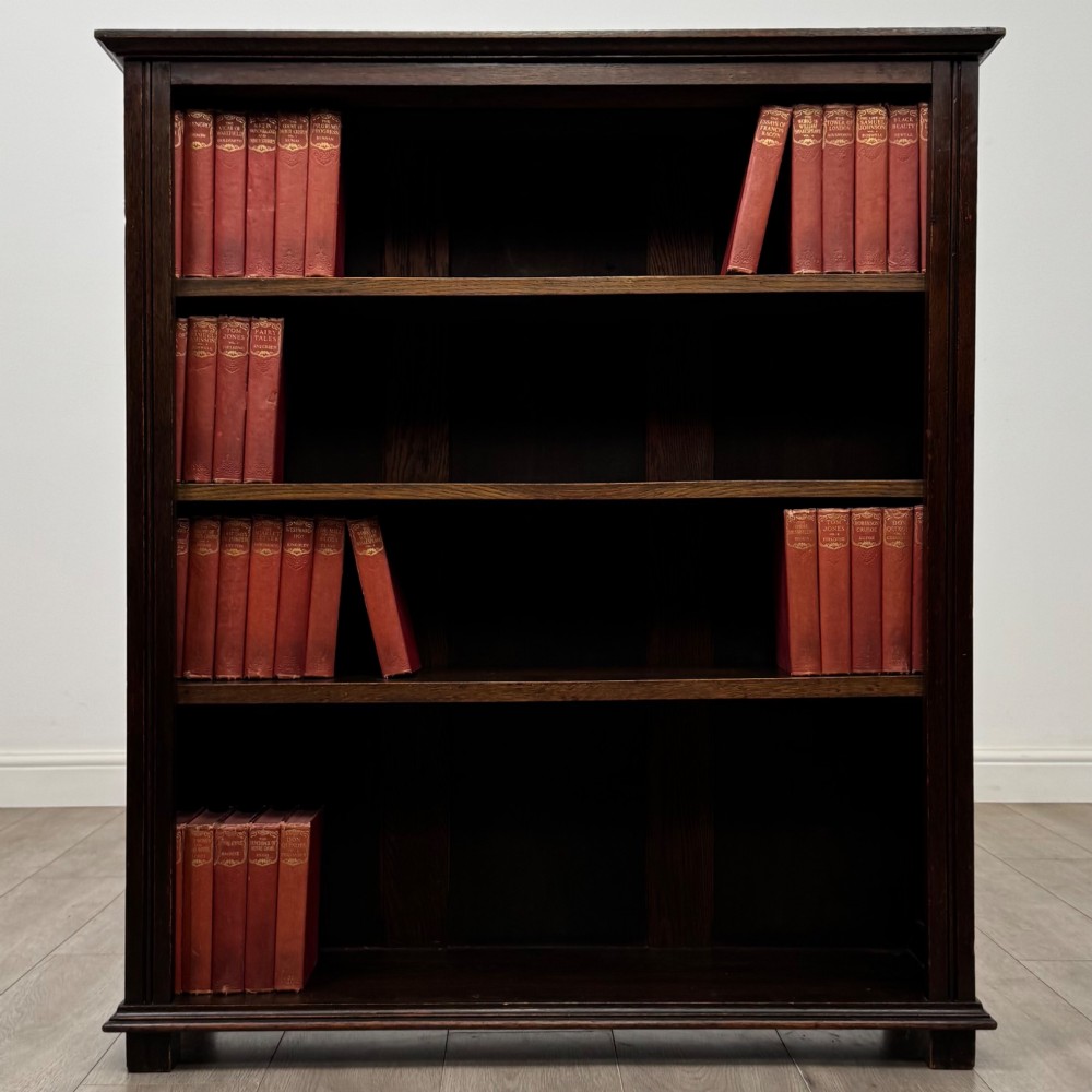 An Edwardian open oak bookcase with four wide shelves and dark timber finish.