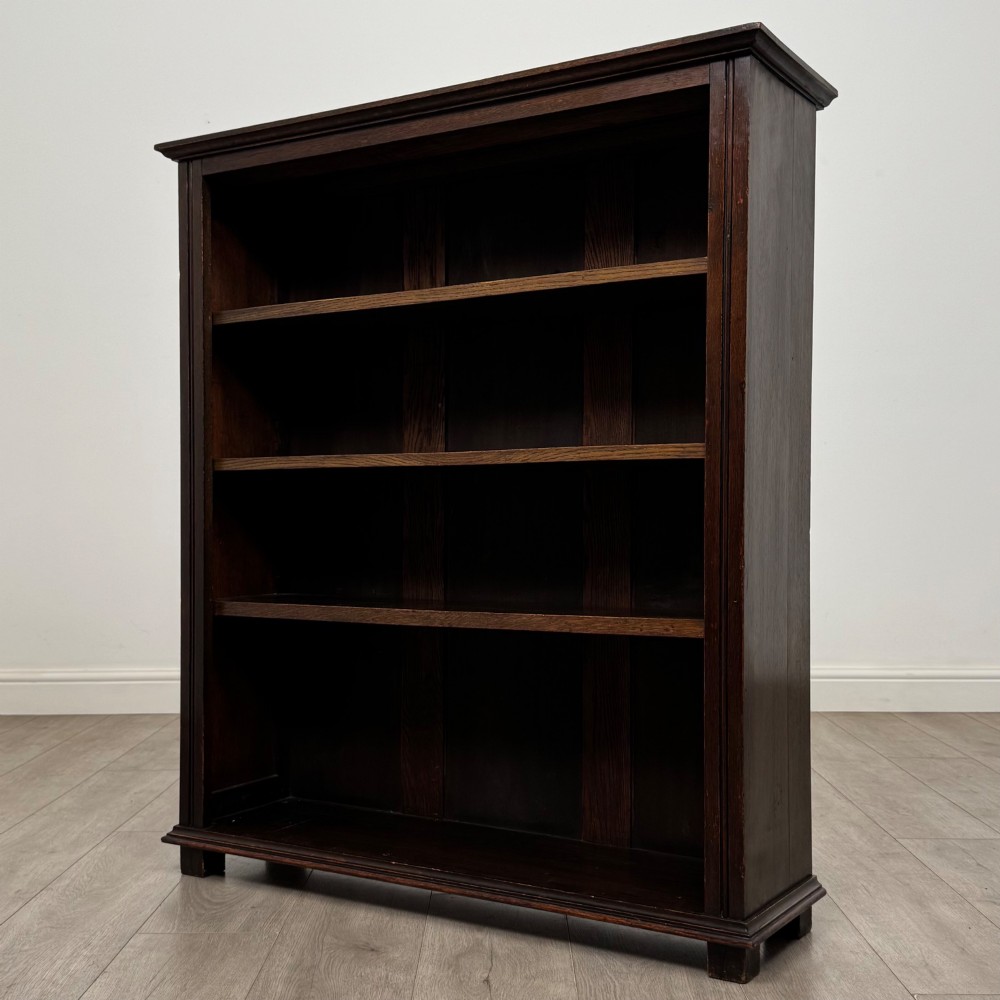 An Edwardian open oak bookcase with four wide shelves and dark timber finish. View III