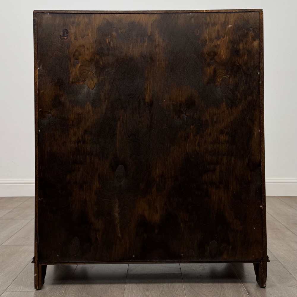 A dark oak writing bureau with a slanted fall-front upper section featuring three carved linenfold panels above four drawers with turned wooden knob handles. View VI