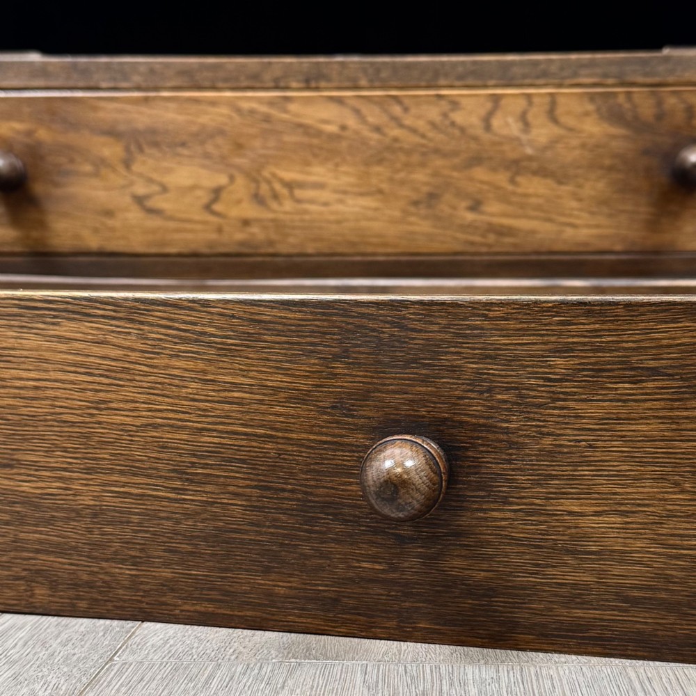 A dark oak writing bureau with a slanted fall-front upper section featuring three carved linenfold panels above four drawers with turned wooden knob handles. View XIII