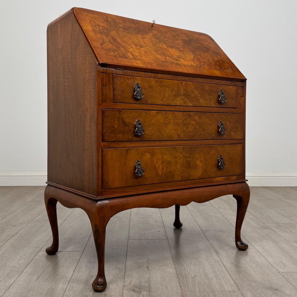 An Edwardian figured walnut writing bureau featuring a slant front above three drawers and carved cabriole legs. View IX