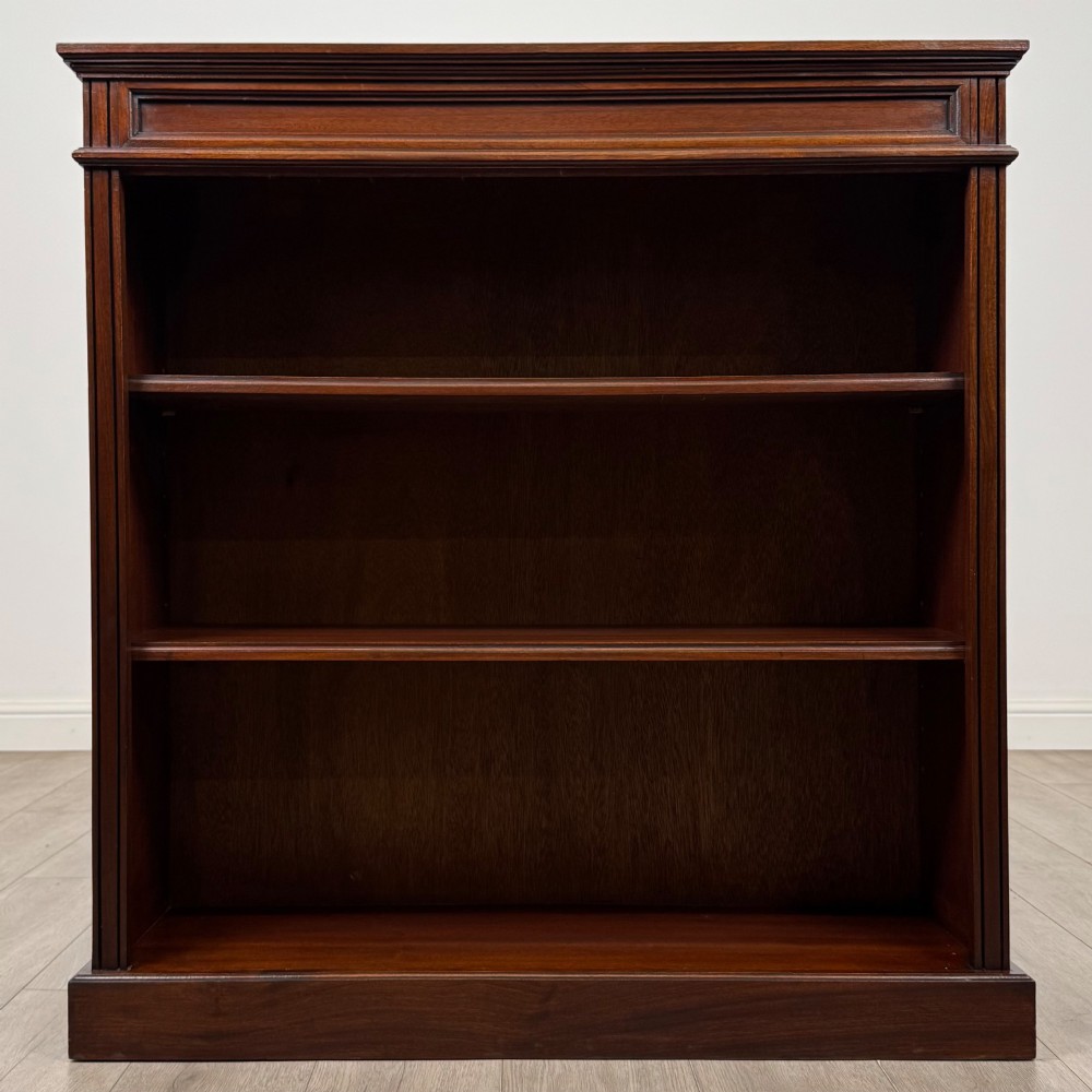 An early twentieth-century open mahogany bookcase featuring three wide horizontal shelves, a heavy moulded cornice, and a solid rectangular plinth base. View II