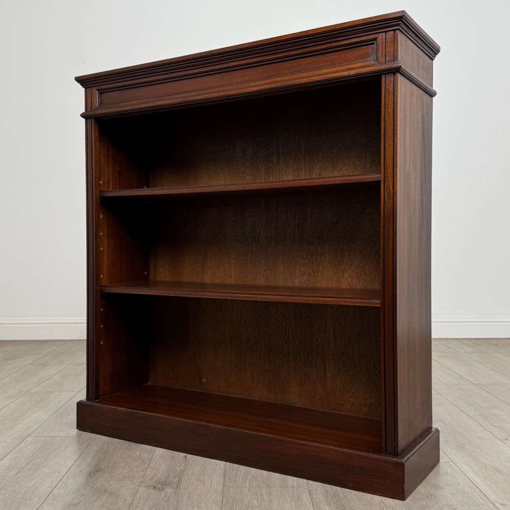 An early twentieth-century open mahogany bookcase featuring three wide horizontal shelves, a heavy moulded cornice, and a solid rectangular plinth base. View III