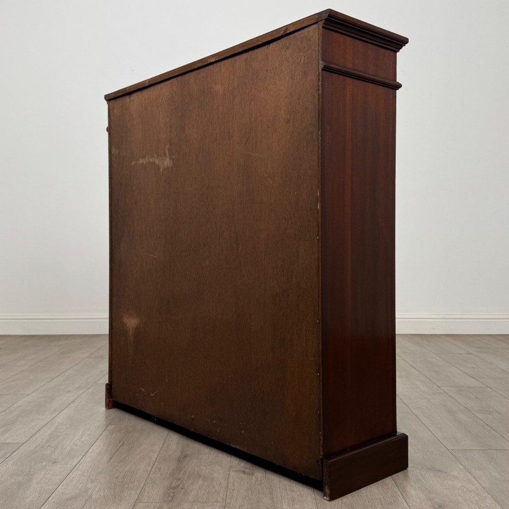 An early twentieth-century open mahogany bookcase featuring three wide horizontal shelves, a heavy moulded cornice, and a solid rectangular plinth base. View VII