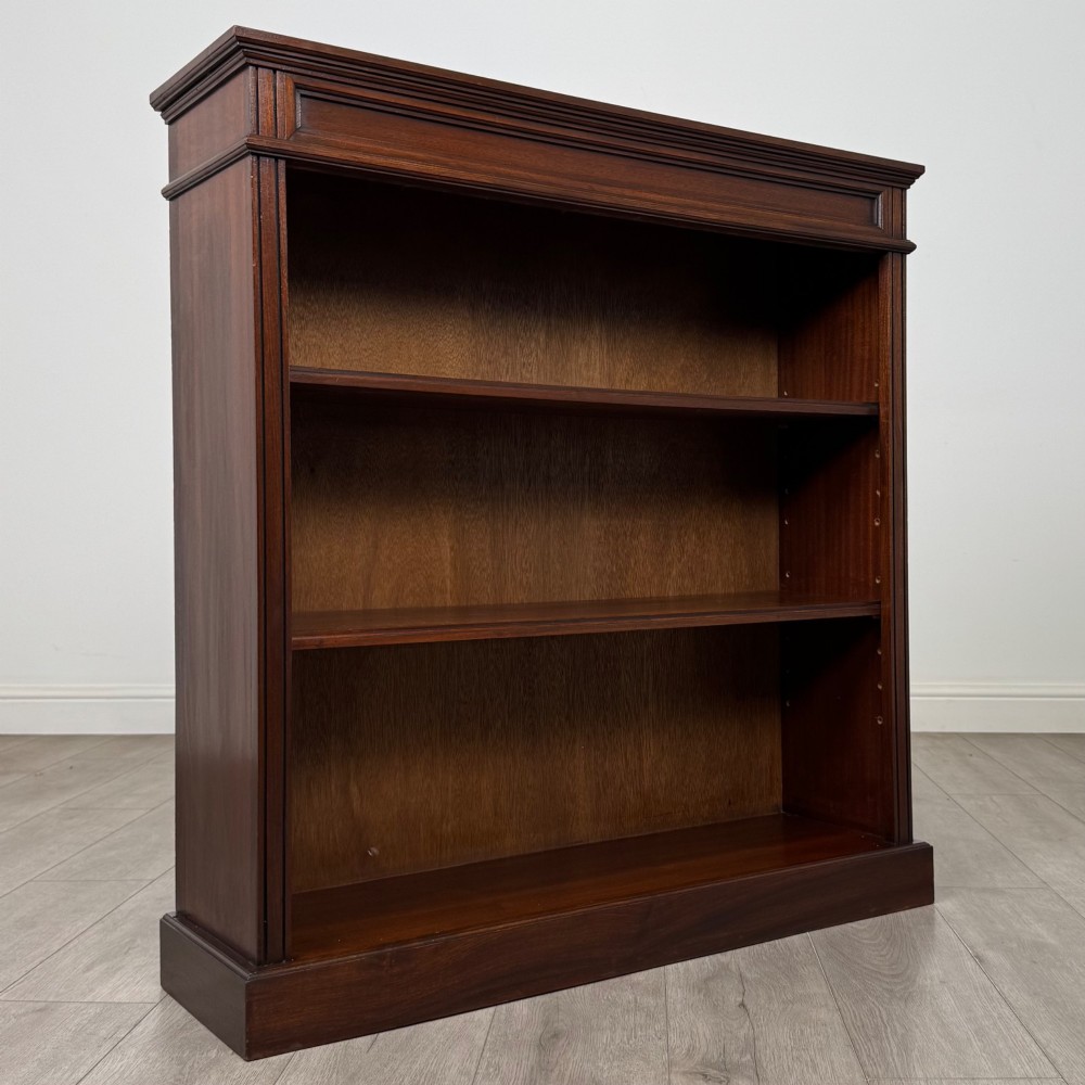 An early twentieth-century open mahogany bookcase featuring three wide horizontal shelves, a heavy moulded cornice, and a solid rectangular plinth base. View IX