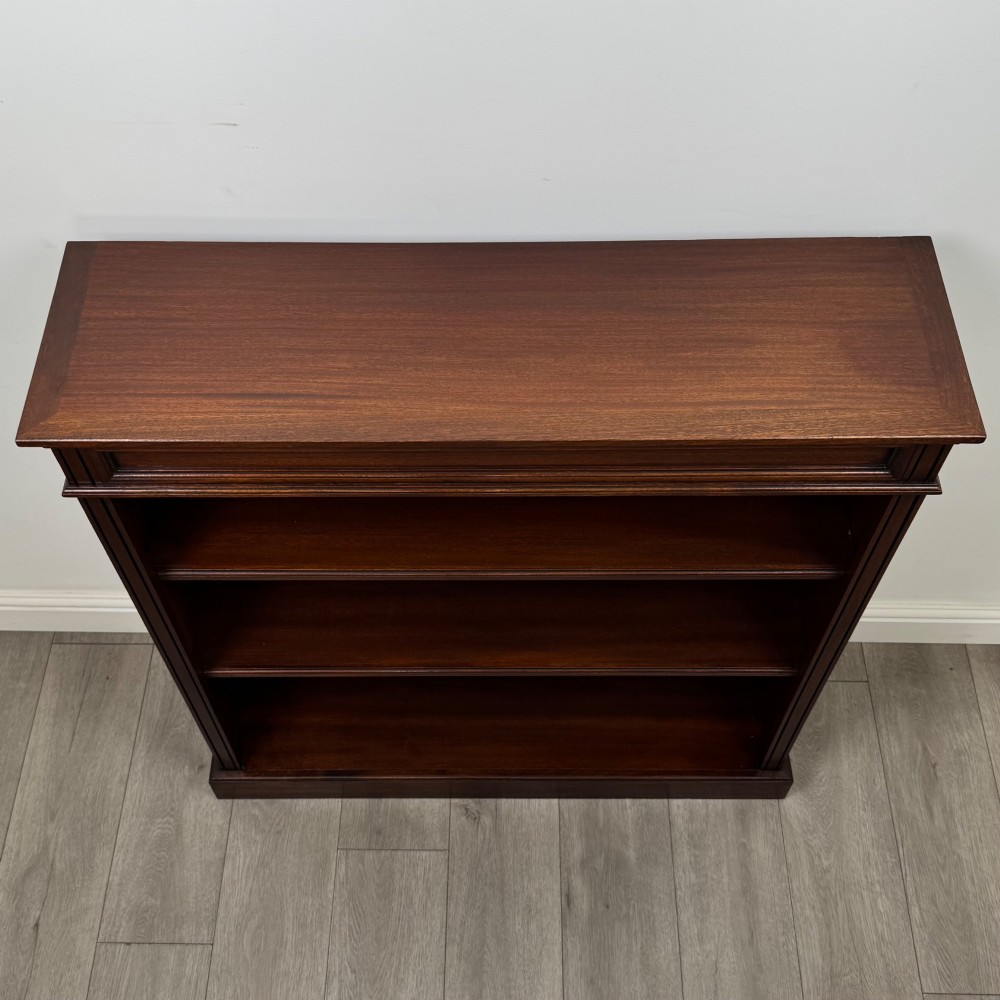 An early twentieth-century open mahogany bookcase featuring three wide horizontal shelves, a heavy moulded cornice, and a solid rectangular plinth base. View X
