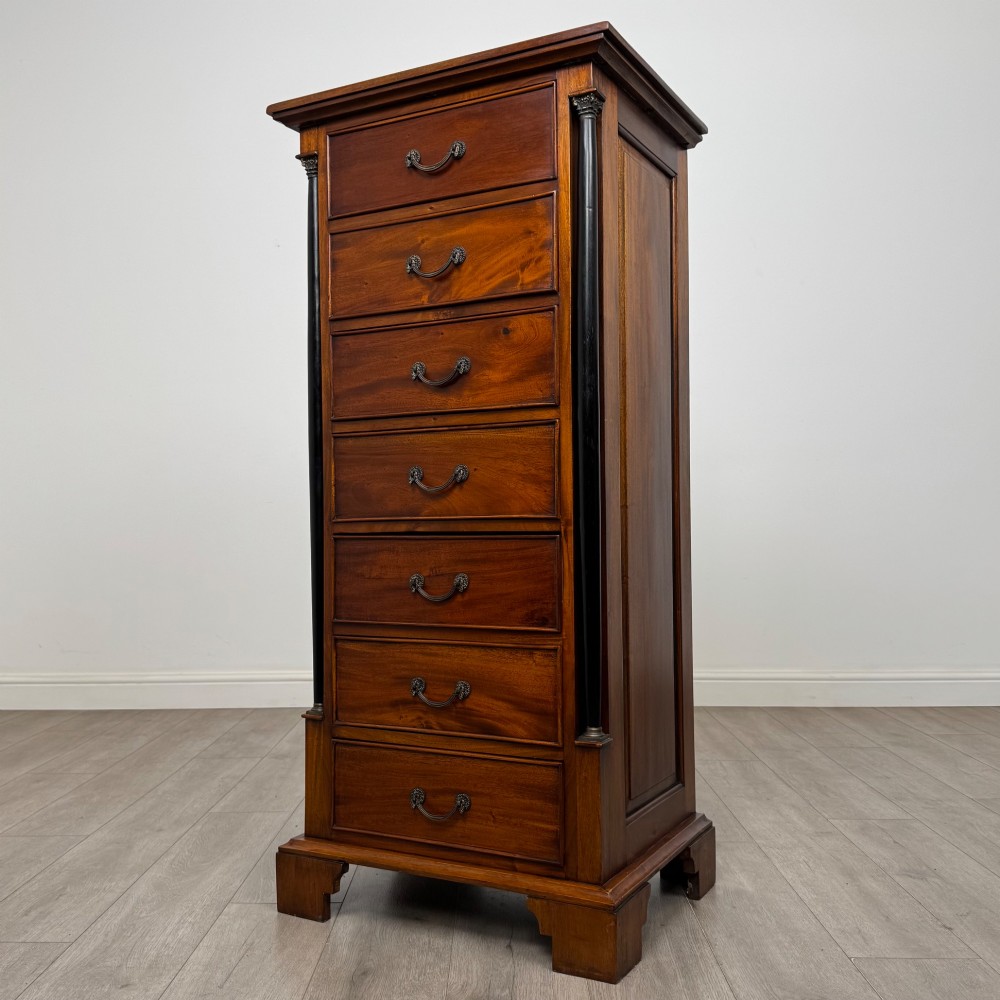 A tall, narrow mahogany chest featuring seven drawers flanked by dark ebonised side columns on bracket feet. View II