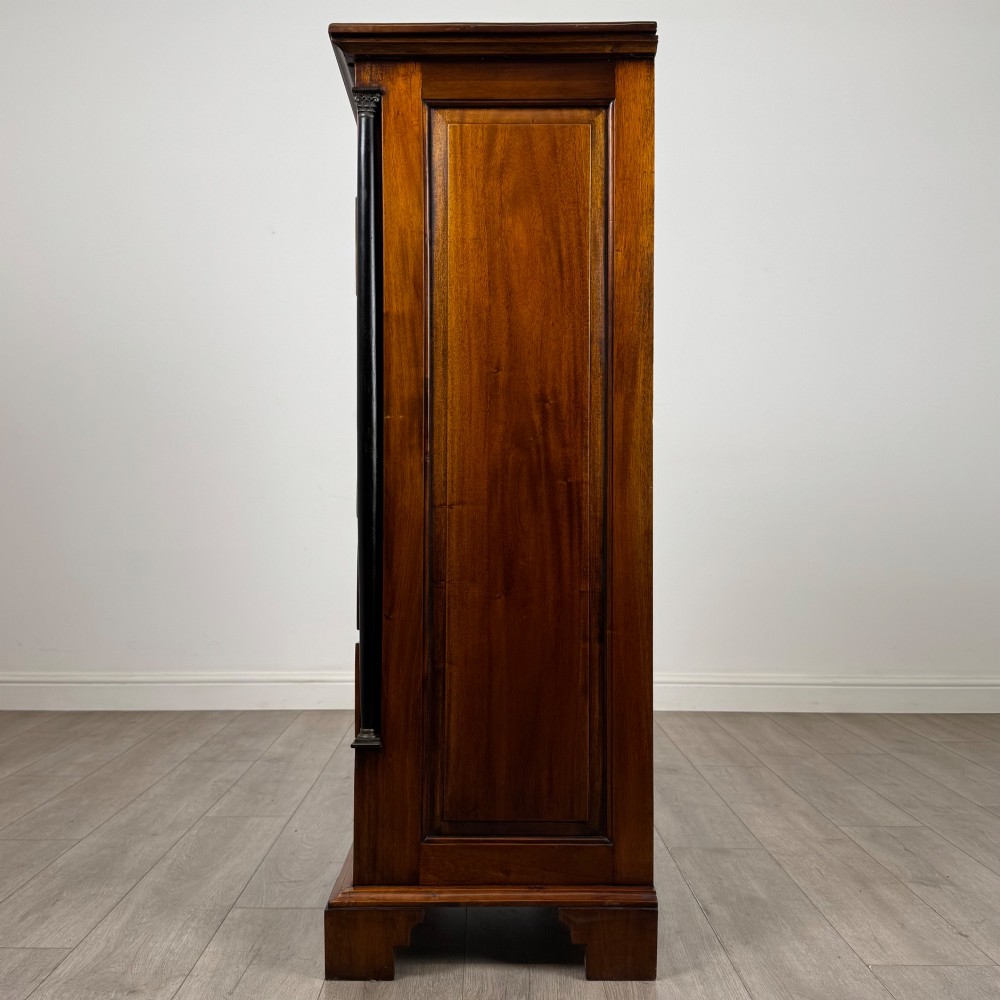 A tall, narrow mahogany chest featuring seven drawers flanked by dark ebonised side columns on bracket feet. View III