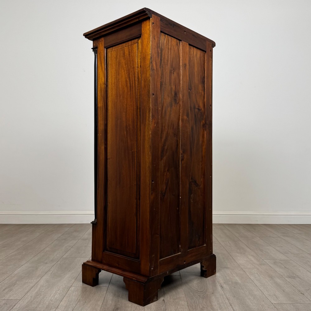 A tall, narrow mahogany chest featuring seven drawers flanked by dark ebonised side columns on bracket feet. View IV