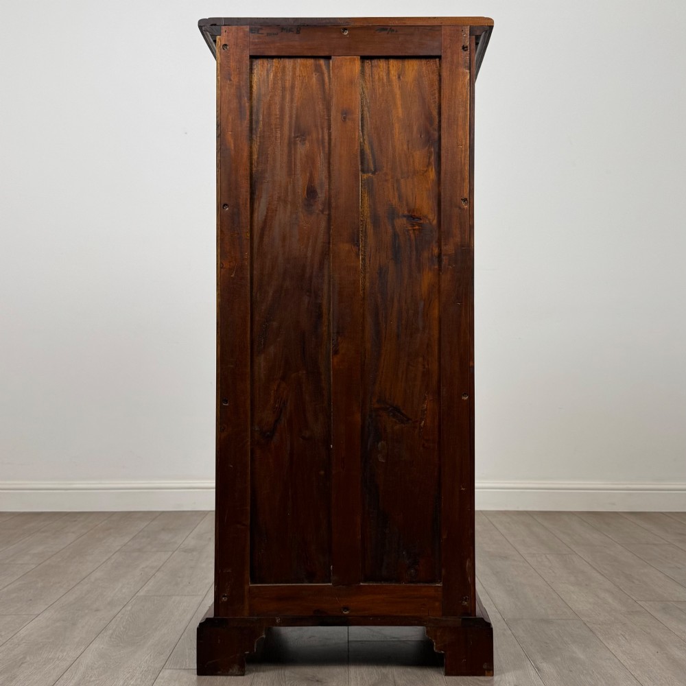A tall, narrow mahogany chest featuring seven drawers flanked by dark ebonised side columns on bracket feet. View V