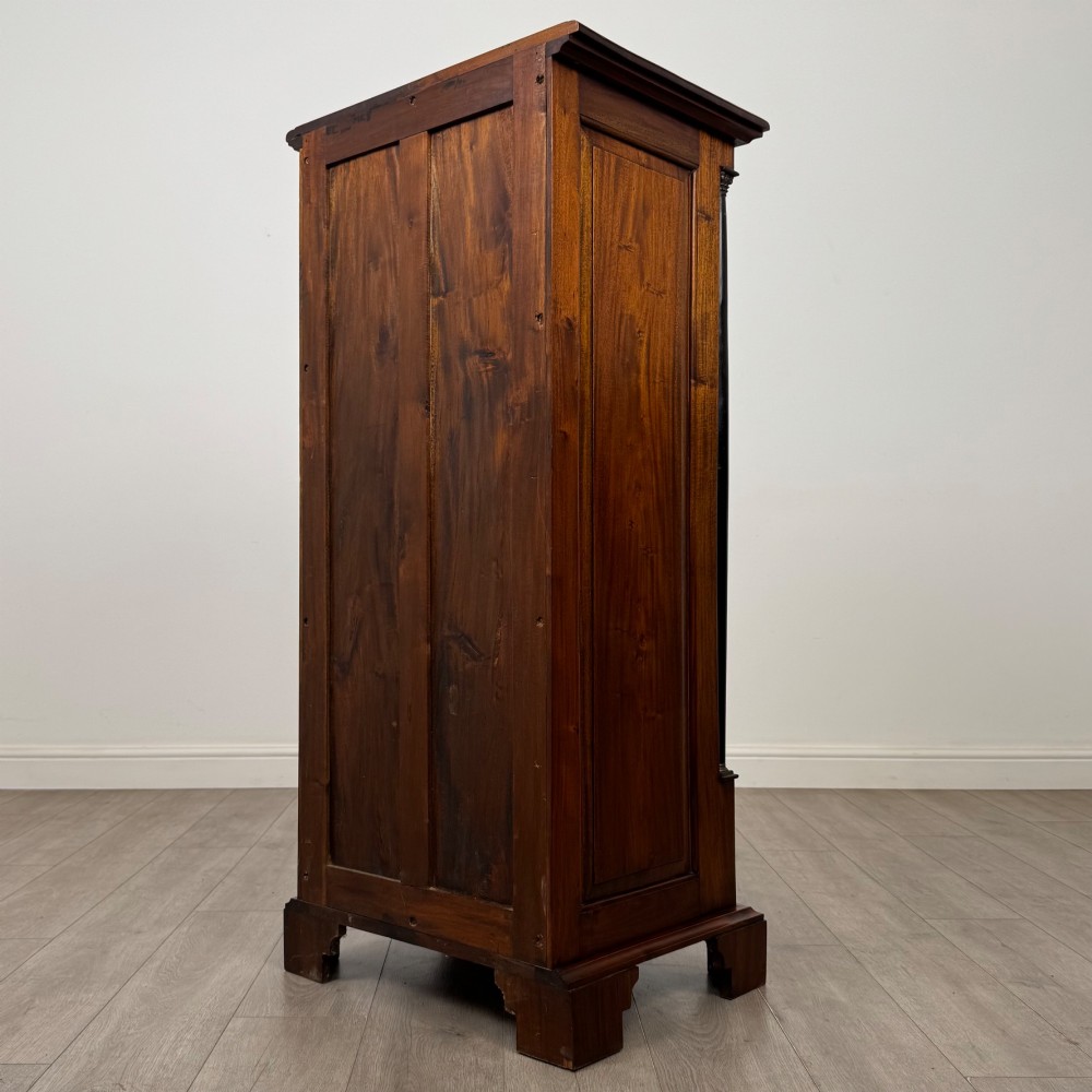 A tall, narrow mahogany chest featuring seven drawers flanked by dark ebonised side columns on bracket feet. View VI