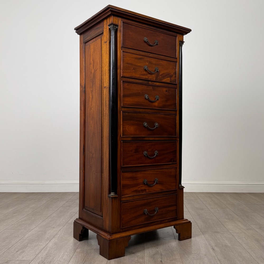 A tall, narrow mahogany chest featuring seven drawers flanked by dark ebonised side columns on bracket feet. View VIII