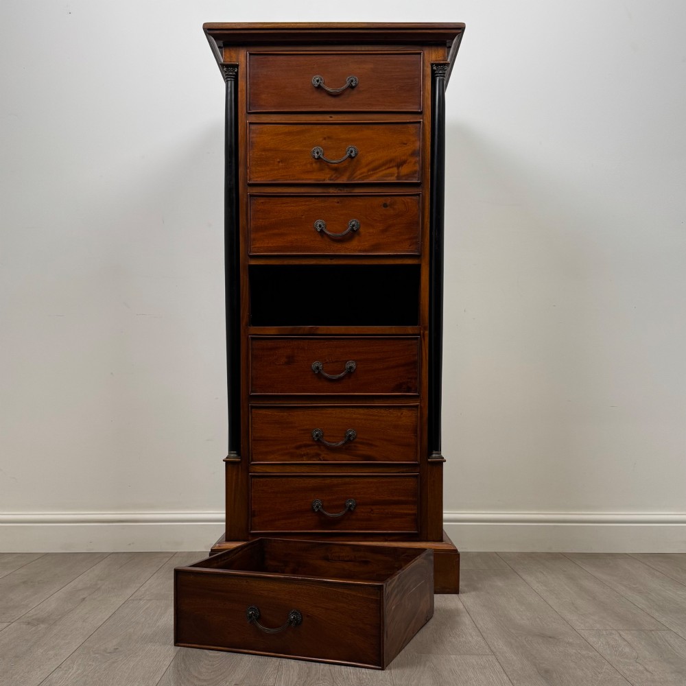 A tall, narrow mahogany chest featuring seven drawers flanked by dark ebonised side columns on bracket feet. View X