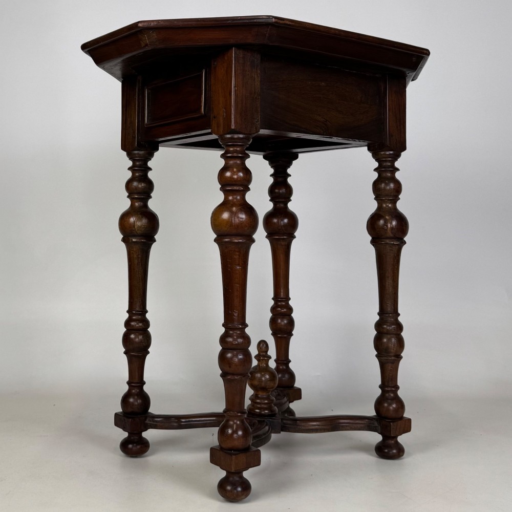 A dark brown hardwood octagonal side table with turned legs, a single drawer with a brass pull, and an arched cross-stretcher featuring a central finial. View IV