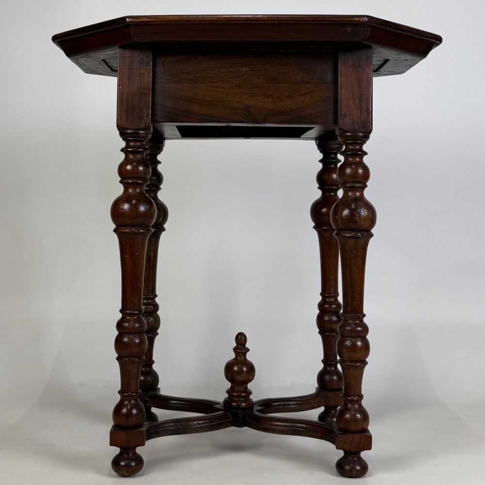 A dark brown hardwood octagonal side table with turned legs, a single drawer with a brass pull, and an arched cross-stretcher featuring a central finial. View V