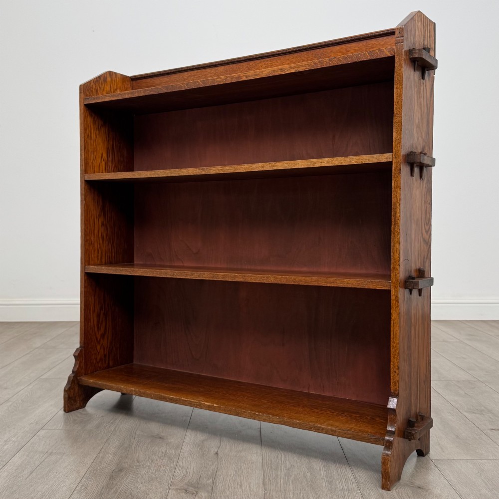 An early twentieth-century open golden oak bookcase featuring four wide wooden shelves and shaped side profile base. View III