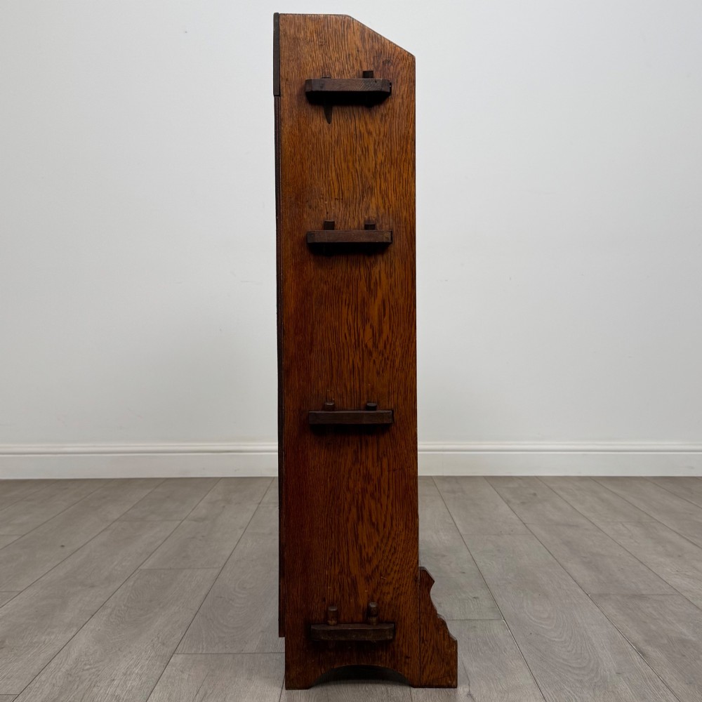 An early twentieth-century open golden oak bookcase featuring four wide wooden shelves and shaped side profile base. View VIII