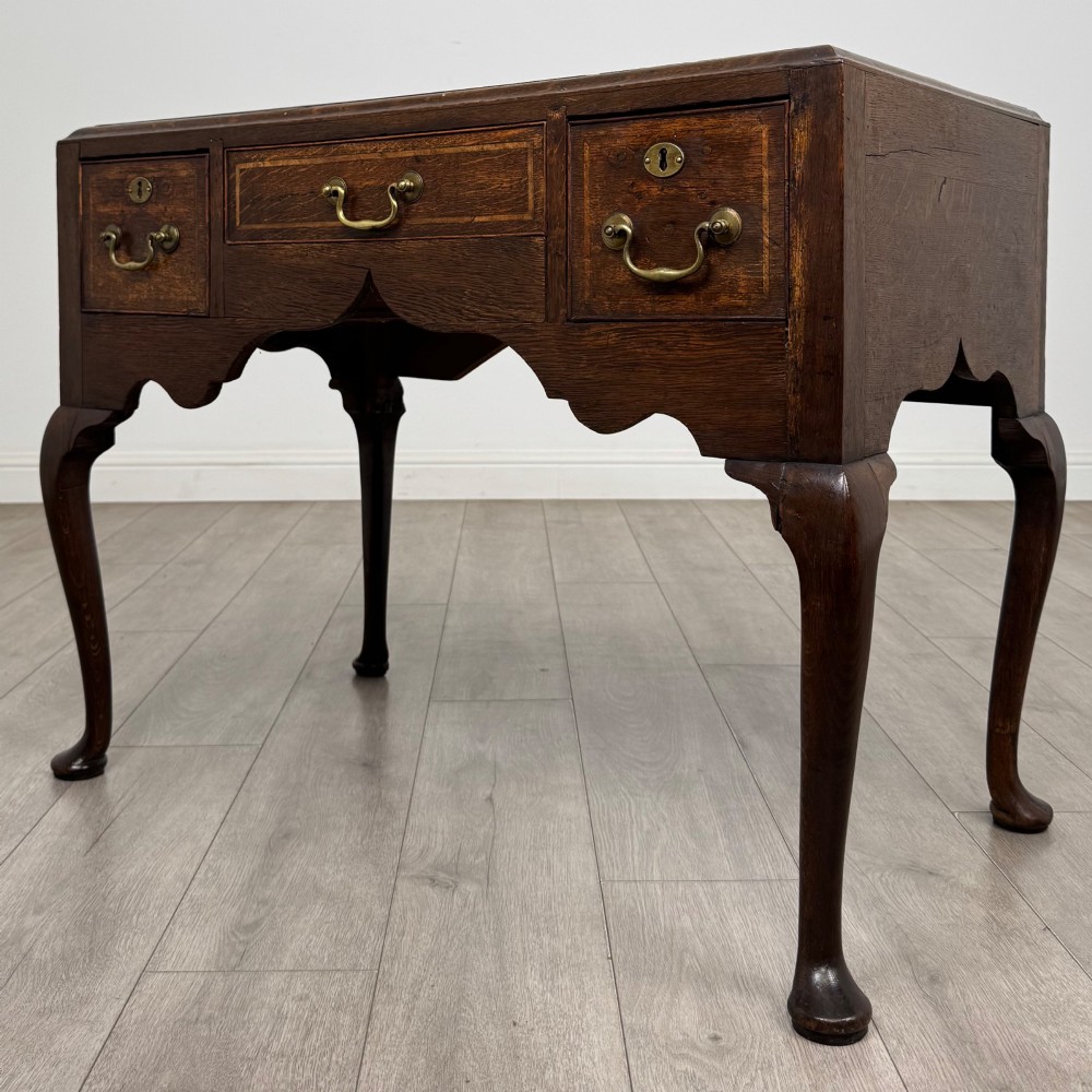 An 18th-century Georgian oak side table featuring three drawers with brass drop handles, an arched apron, and cabriole legs. View II