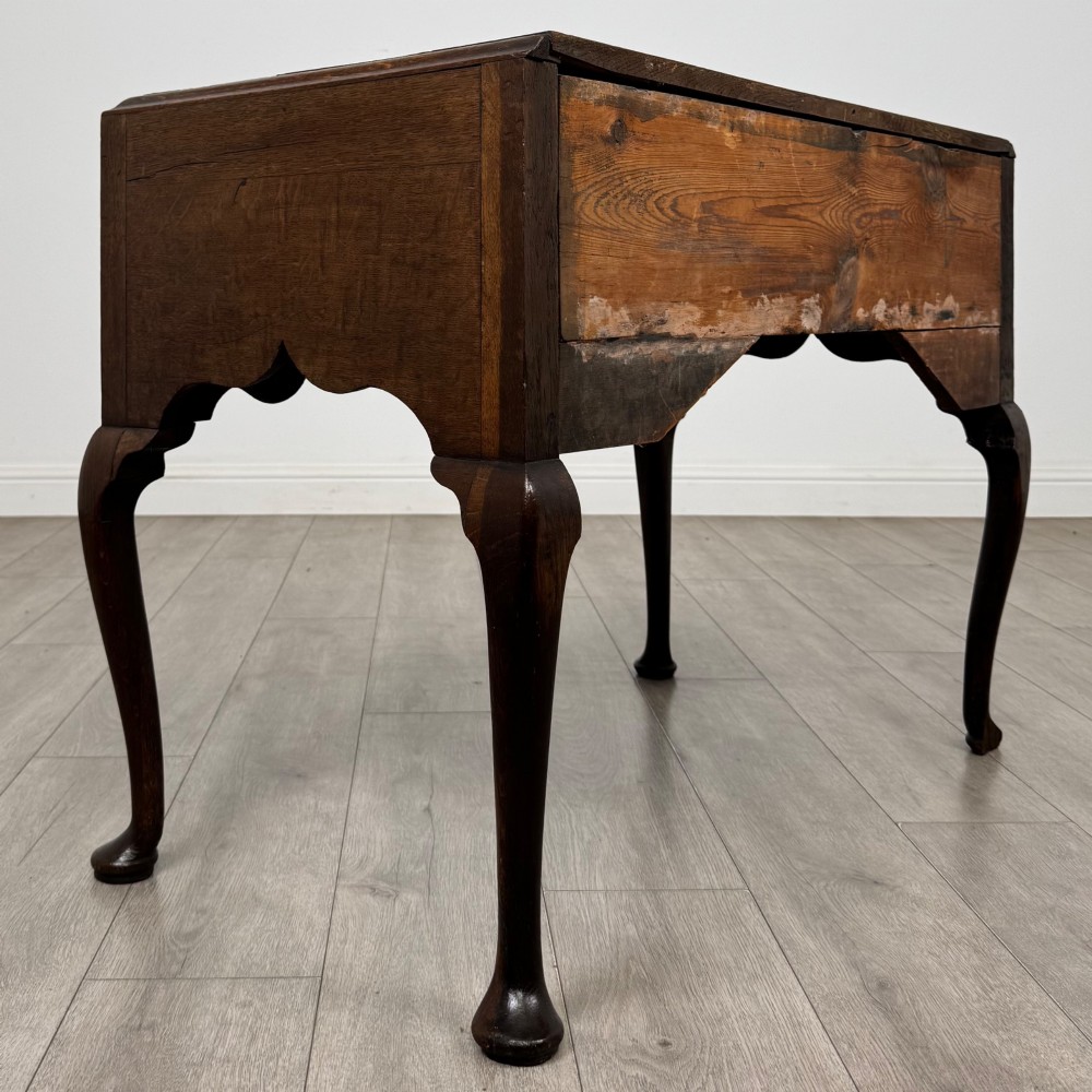 An 18th-century Georgian oak side table featuring three drawers with brass drop handles, an arched apron, and cabriole legs. View IV